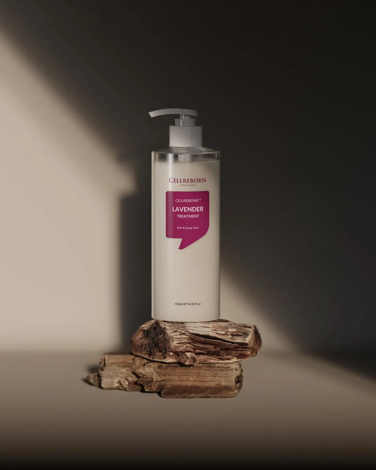 Cellrebiome Lavender Treatment bottle on a piece of wood with a diagonal shaft of light and deep shadow