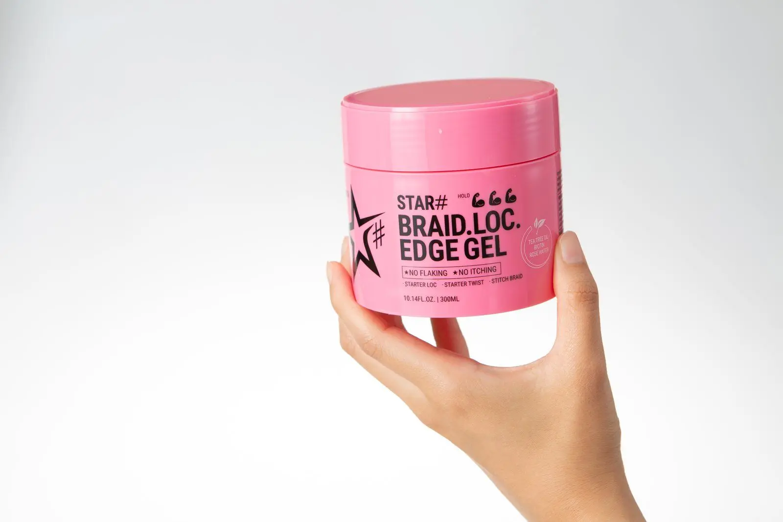 A hand holding a pink CELLREBORN STAR# Braid Loc Edge Gel jar against a white backdrop